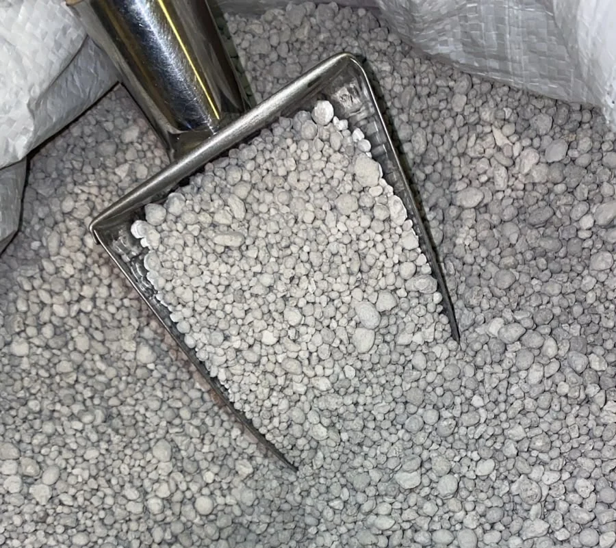 Single super phosphate (SSP) granules in a metal scoop inside a woven bag